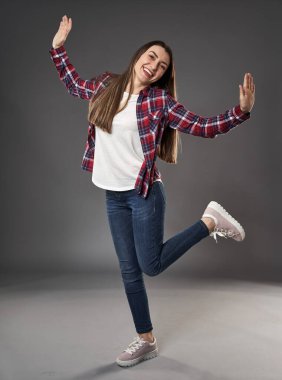 Gri arka planda, ekose gömlekli genç bir kadının boyu.