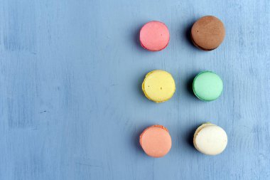 Mavi arka planda çeşitli renkli ve aromalı badem kurabiyelerinin düz görüntüsü.