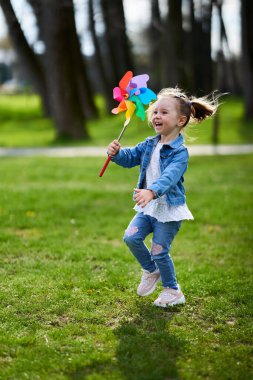 Küçük kız parkta fırıldak ile oynuyor.
