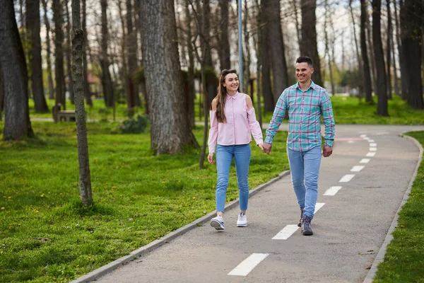 美しい春の日に公園の路地を歩く若いカップル — ストック写真