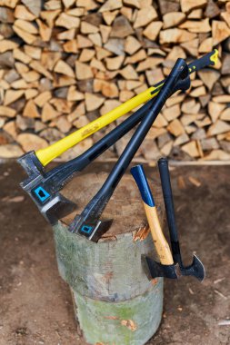 Bir odun yığınının üzerinde bir sürü hafif ve ağır balta var.