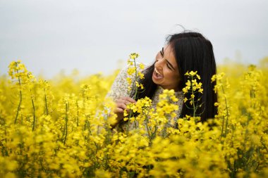 Çiçekli kanola tarlasında güzel esmer, İspanyol bir genç kadın.