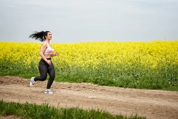 加尺寸漂亮的拉丁女子在水牛田边的土路上慢跑 — 图库照片
