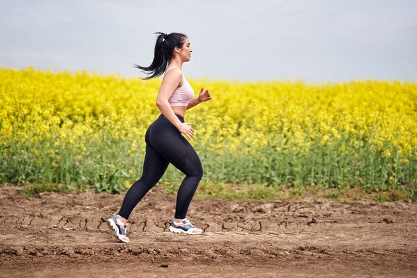 加尺寸漂亮的拉丁女子在水牛田边的土路上慢跑 — 图库照片
