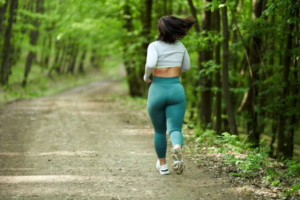 美丽又大的女跑步者在森林的土路上奔跑 — 图库照片