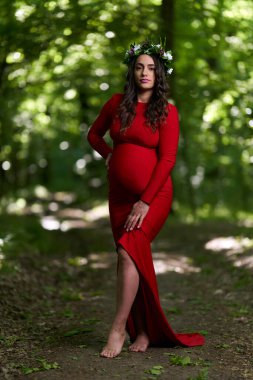 Yazın yaprak döken bir ormanda uzun kırmızı elbiseli güzel bir İspanyol kadının portresi.