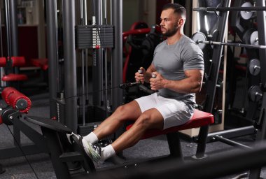 Atletik adam kablo sırası makinesinde egzersiz yapıyor.