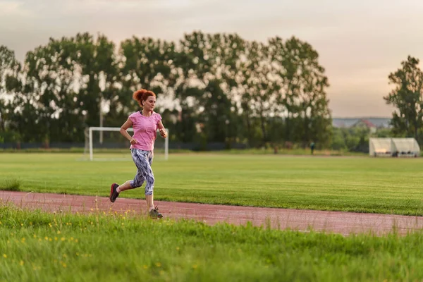 日落时在城里的一条跑道上奔跑的女人 — 图库照片