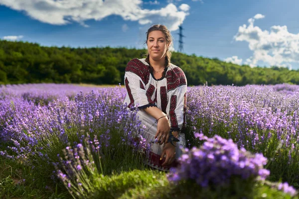 身着罗马尼亚传统服装的年轻女子从花园采摘薰衣草 — 图库照片