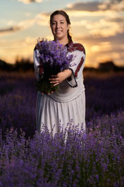 Geleneksel Romen kostümlü genç kadın bahçesinden lavanta topluyor