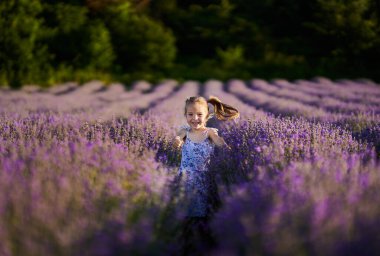 Sevimli küçük kız lavanta tarlasında koşuyor