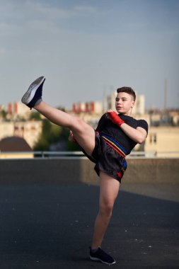 Genç kickboksör dövüşçüleri çatıda eğitim görüyor. Arka planda binalar, şehir savaşçısı...