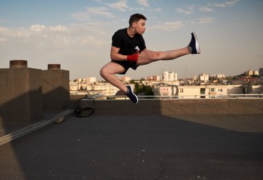 Genç kickboksör dövüşçüleri çatıda eğitim görüyor. Arka planda binalar, şehir savaşçısı...