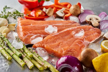 Paslanmaz çelik kesme tahtasında buzlu sebzeli taze çiğ somon filetosu.