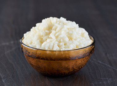 Ahşap bir tahtanın üzerinde haşlanmış pirinçle dolu bir kase.