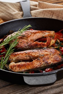 Dökme demir tava Alaska yabani somonunu kiraz domatesli, biberli, mantarlı, soğanlı ve otlu pişirdi.