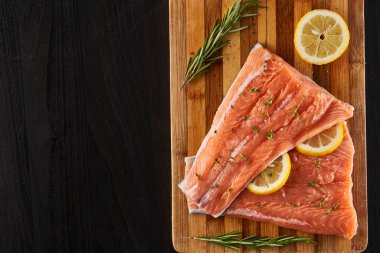 Çiğ somon fileto limon ve ahşap bir tahtanın üzerinde otlar, pişirmeye hazır.