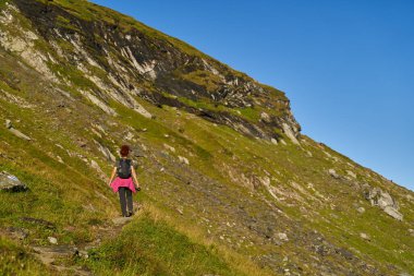 Yaz sonunda sırt çantalı bir turist kayalık dağlarda yürüyüş yapıyor.