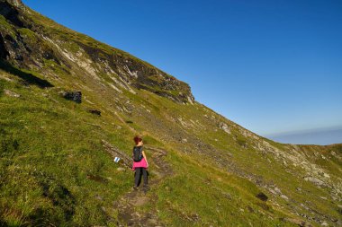 Yaz sonunda sırt çantalı bir turist kayalık dağlarda yürüyüş yapıyor.