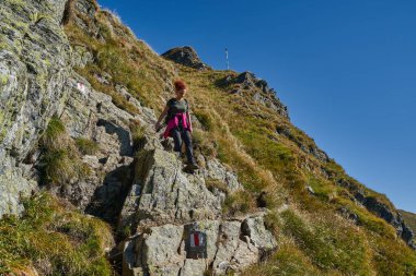 Yaz sonunda sırt çantalı bir turist kayalık dağlarda yürüyüş yapıyor.