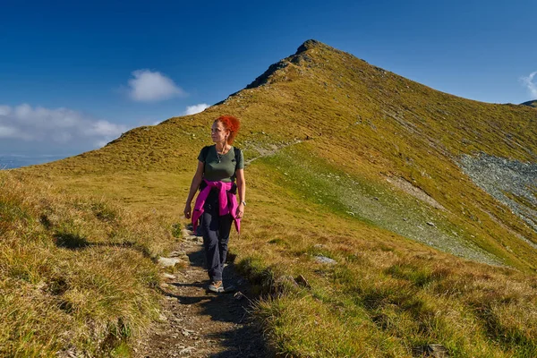 岩の多い山の中のトレイルでバックパックハイキングをする女性観光客 夏の終わり — ストック写真