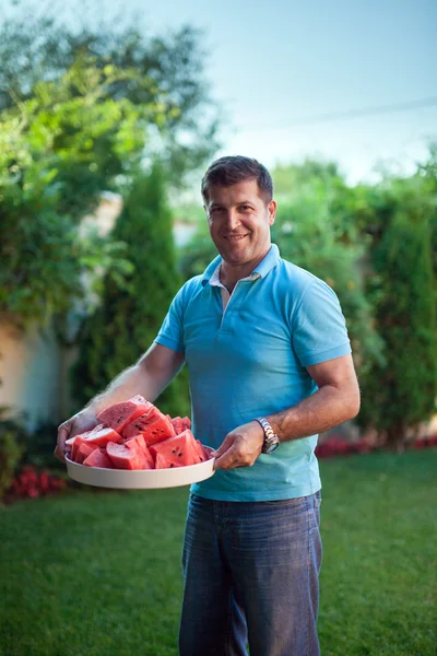 Homem com um prato de melancia fatiada — Fotografia de Stock