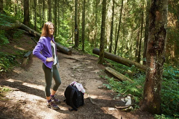 Vrouw met rugzak wandelen in het bos — Stockfoto