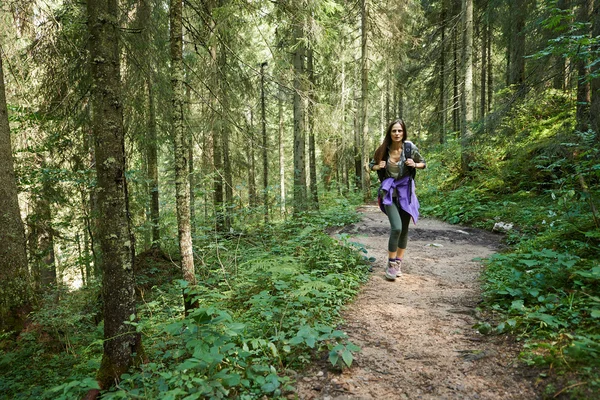 Kvinna med ryggsäck vandring in i skogen — Stockfoto