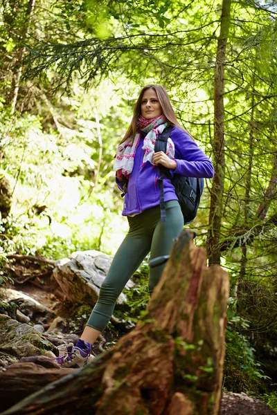 Mulher com mochila caminhando na floresta — Fotografia de Stock