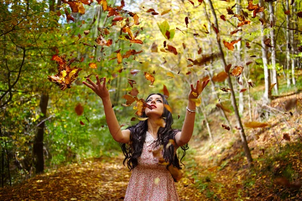 Mulher jogando folhas no ar — Fotografia de Stock