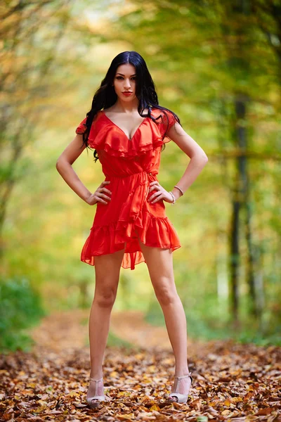 Kvinna i röd klänning i skogen — Stockfoto