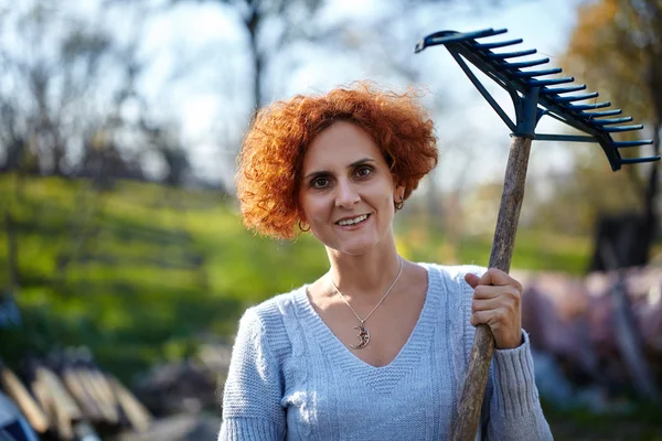 Femme avec râteau nettoyage jardin — Photo