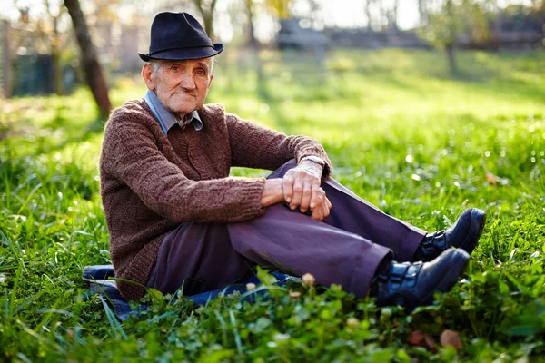 Stary rolnik siedzący w trawie — Zdjęcie stockowe