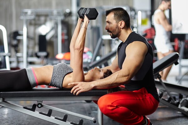 Fitness instructor assisting young woman