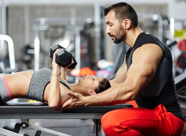 Fitness instructor assisting young woman