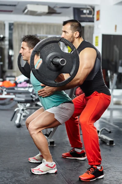 Doing barbell squats with personal instructor — Stock Photo, Image