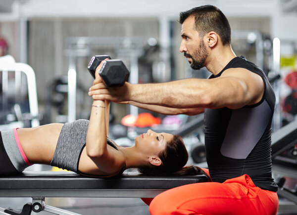 Personal trainer assisting young woman