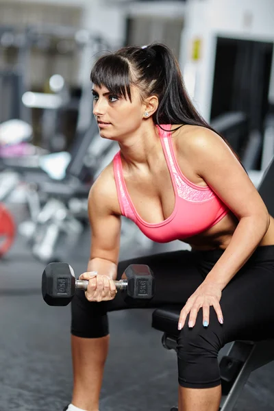 Menina fazendo exercícios de bíceps em um ginásio — Fotografia de Stock