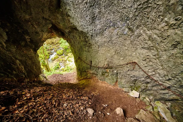 Cave entrance with safety cable on the wall — Stock Photo, Image