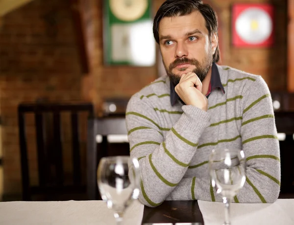 Junger schöner Mann sitzt in einem Restaurant — Stockfoto