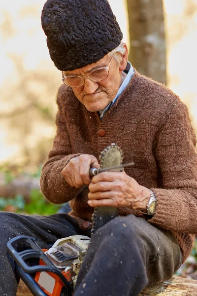 Starší zemědělce servis svou pilou po použití — Stock fotografie