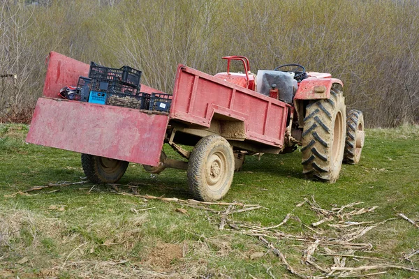 Alter schmutziger Traktor mit Anhänger auf einem Feld — Stockfoto