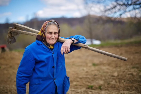 Senior woman with two hoes — Stock Photo, Image