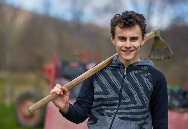 Tiener jongen met een schoffel buiten — Stockfoto