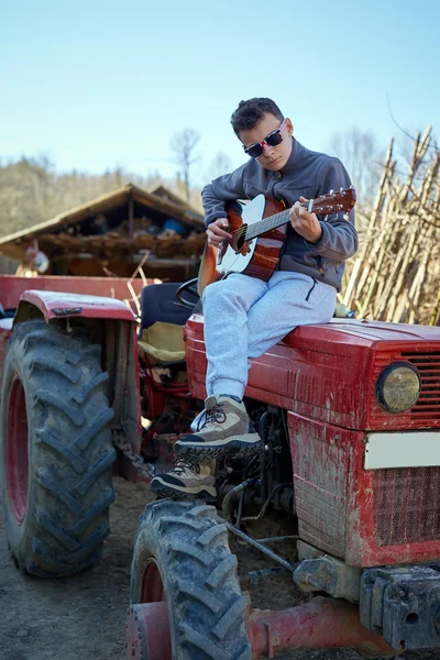 Хлопчик-підліток грає на гітарі на тракторі — стокове фото