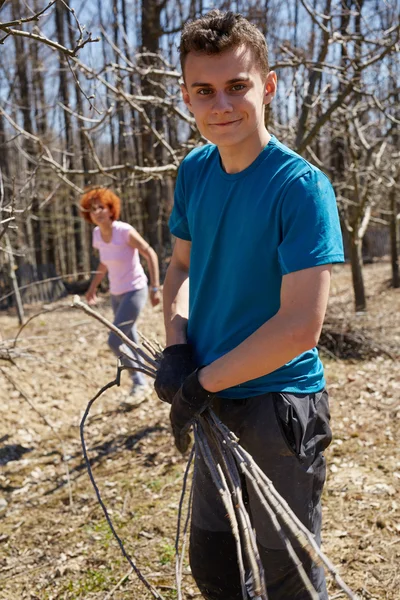 Jugendlicher Junge und seine Mutter beim Frühjahrsputz im Obstgarten — Stockfoto