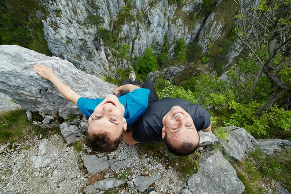 Батько і син сидять на краю скелі — стокове фото