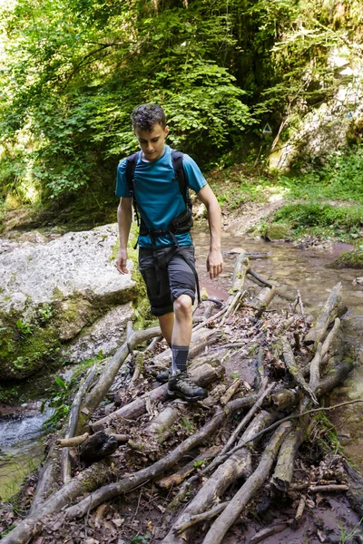 Junge überquert einen Bergfluss — Stockfoto