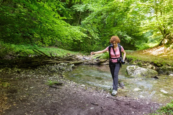 Kvinna hiker korsar floden Stockfoto