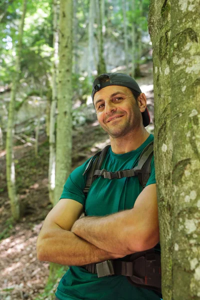 Homme avec sac à dos appuyé contre un arbre — Photo